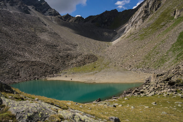 Das Bild zeigt den See blaugrün schimmernd in karger Berglandschaft.