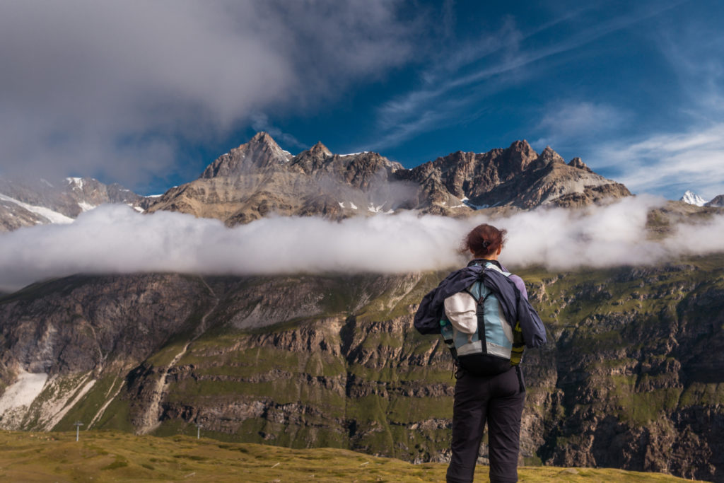Das Bild zeigt eine Wanderin, die Richtung Berge blickt.