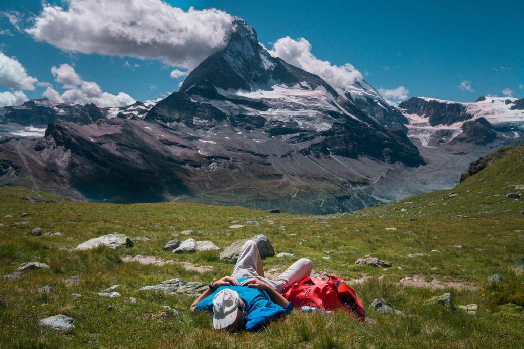 Ein Wanderer liegt im Gras und blickt auf das Matterhorn